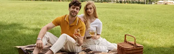 Elegantes Paar in stilvoller Kleidung genießt einen gemütlichen Moment auf einer Picknickdecke inmitten einer üppigen Parklandschaft. — Stockfoto