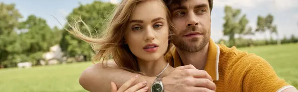 A stylish couple dressed elegantly in a field, sharing a warm embrace, embodying wealth and sophistication. — Stock Photo