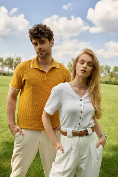 A stylish couple stands in a lush field, enjoying a moment of togetherness under the open sky. — Stock Photo
