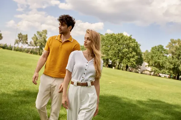 Красива молода пара одягнена елегантно йде разом у парк, насолоджуючись компанією один одного на зеленому тлі. — стокове фото