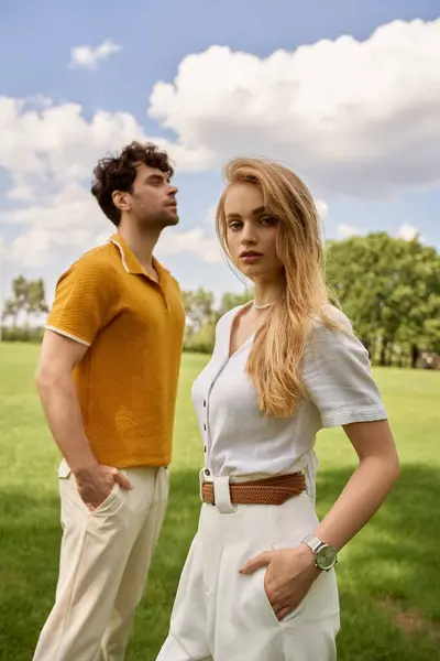 A stylish man and woman embrace in a lush green field, embodying an affluent and timeless connection with nature. — Stock Photo