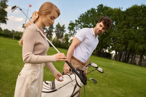 A man and woman in elegant attire stand together on a lush golf course, embodying a refined display of leisure and sophistication. — Stock Photo