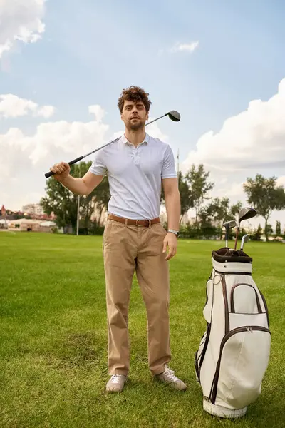 Um homem de traje elegante está em um campo de golfe com um saco de golfe, incorporando um estilo de dinheiro antigo e estilo de vida de classe alta. — Fotografia de Stock