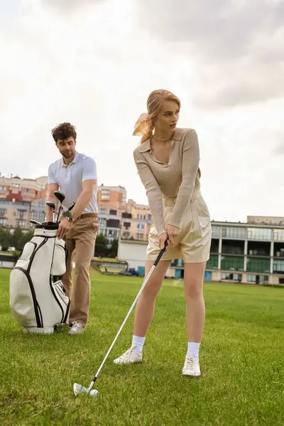 Un uomo e una donna alla moda stanno giocando a golf su un lussureggiante campo verde in un club prestigioso, godendosi reciprocamente la compagnia.. — Foto stock