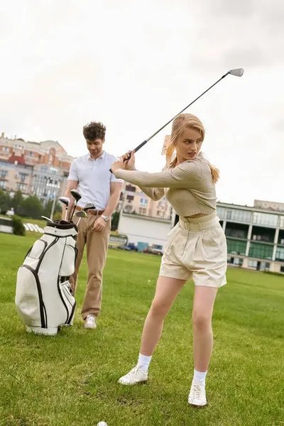 Jeune couple en tenue élégante jouissant d'un jeu de golf sur un terrain verdoyant dans un prestigieux club de golf. — Photo de stock