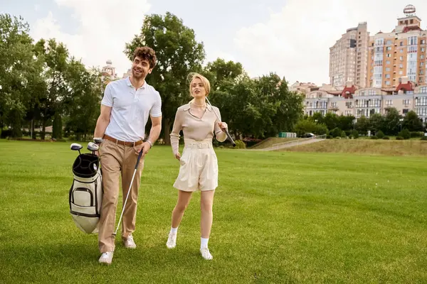 Um casal elegante caminhadas de lazer em um campo de golfe luxuoso, cercado pela vegetação da paisagem serena. — Fotografia de Stock