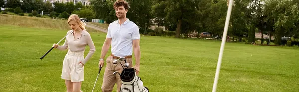 A young couple in elegant attire stands together on a golf course, embracing the upper-class lifestyle of old money. — Stock Photo