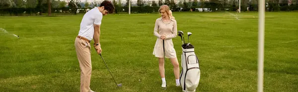 Una giovane coppia in elegante abbigliamento giocare a golf su un campo verde lussureggiante, godendo il loro tempo insieme in un ambiente di classe. — Foto stock