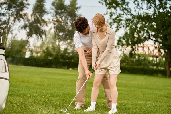 Um jovem casal em trajes elegantes desfrutar de um jogo de golfe em um campo verde exuberante em um ambiente de clube de golfe de classe alta. — Fotografia de Stock