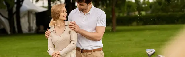 Um jovem casal em trajes elegantes abraça calorosamente em um campo verde exuberante em um clube de golfe, incorporando um dinheiro velho, estilo de vida de classe alta. — Fotografia de Stock