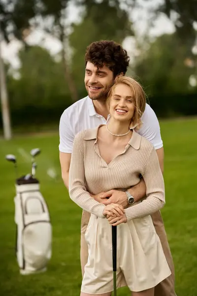 A stylish couple in formal attire posing on a golf course surrounded by lush greenery. — Stock Photo