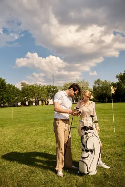 A young couple, dressed in elegant attire, stands on a lush green golf course enjoying a moment together. — Stock Photo