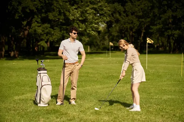 Un uomo e una donna alla moda giocare a golf su un campo verde incontaminato, incarnando un vecchio denaro eleganza e stile di vita di classe superiore. — Foto stock