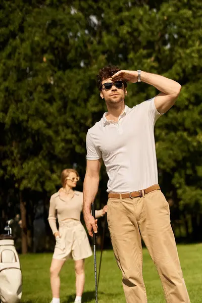 A man and a woman in elegant attire stand together on a golf course, embodying an old-money style and upper-class lifestyle. — Stock Photo