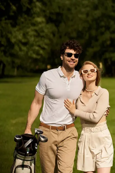Um jovem e uma mulher fazem uma pose elegante em um ambiente exuberante no parque, desfrutando de um dia de trajes elegantes. — Fotografia de Stock