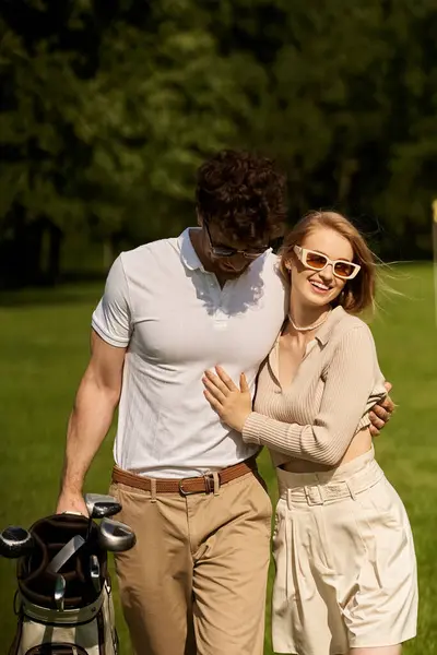 A stylish young man and woman stand close together on a lush green golf course, exuding elegance and sophistication. — Stock Photo