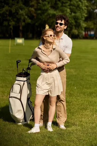 A young couple in elegant attire standing together on a lush green golf course, embracing the upscale atmosphere. — Stock Photo
