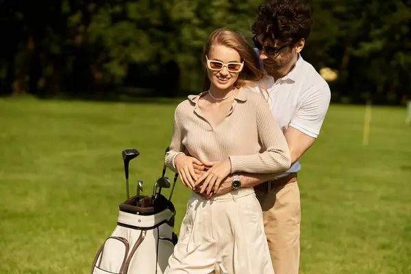 Un jeune couple en tenue élégante partage une étreinte amoureuse sur un terrain de golf verdoyant, entouré de luxe et de charme d'argent ancien. — Photo de stock