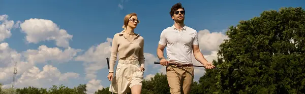 A young couple in elegant clothing walks across a luxurious golf course, enjoying the refined atmosphere. — Stock Photo