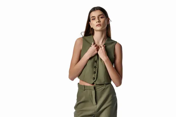 A beautiful woman with long dark hair poses in stylish green top and pants against a gray backdrop. — Stock Photo
