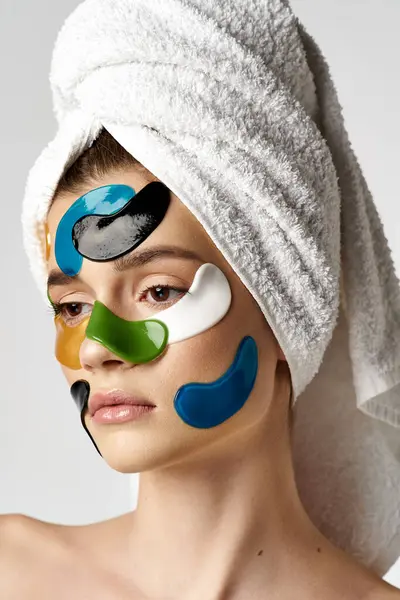 Uma jovem mulher com uma toalha enrolada em torno de sua cabeça com manchas nos olhos em seu rosto. — Fotografia de Stock