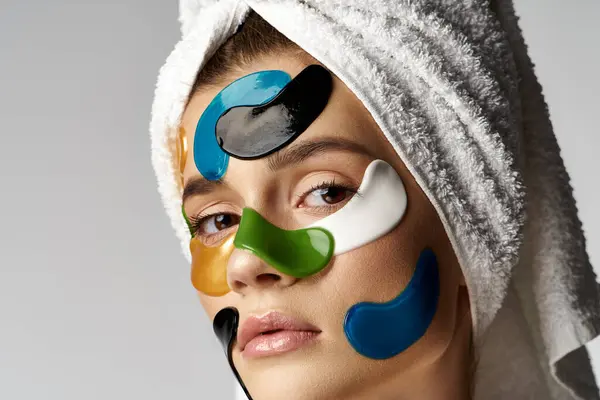 Una mujer con una toalla en la cabeza, con manchas en los ojos en la cara. - foto de stock