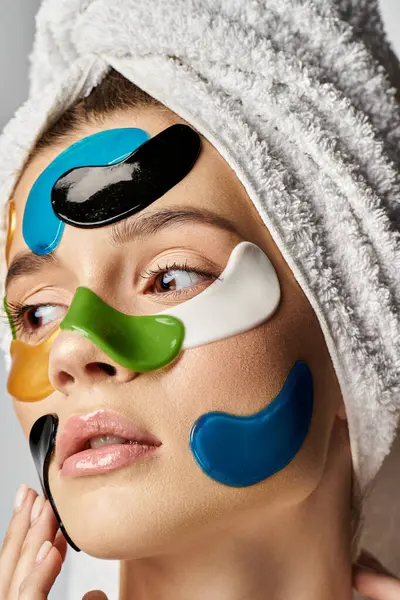 Debonair woman with a towel wrapped around her head and eye patches. — Stock Photo