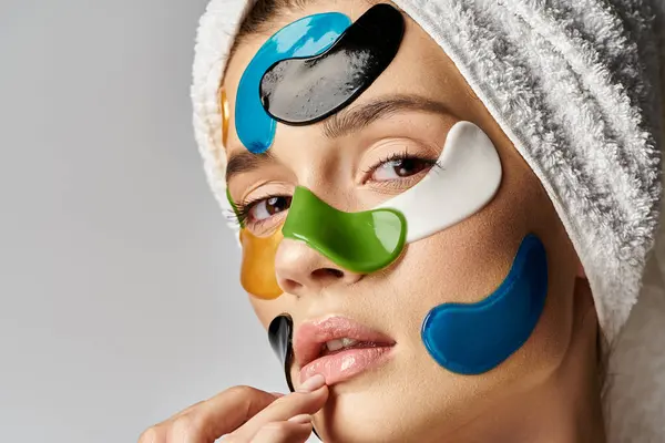 Молода жінка позує з плямами очей на обличчі і рушником, загорнутим навколо голови, демонструючи художній і ефірний вигляд. — стокове фото