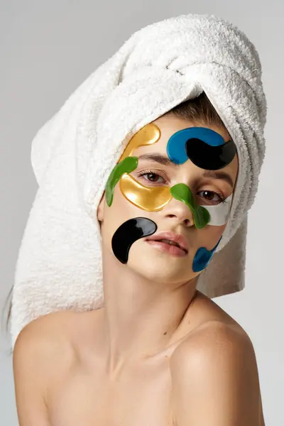 Hermosa joven con una toalla envuelta alrededor de su cabeza y parches para los ojos. - foto de stock
