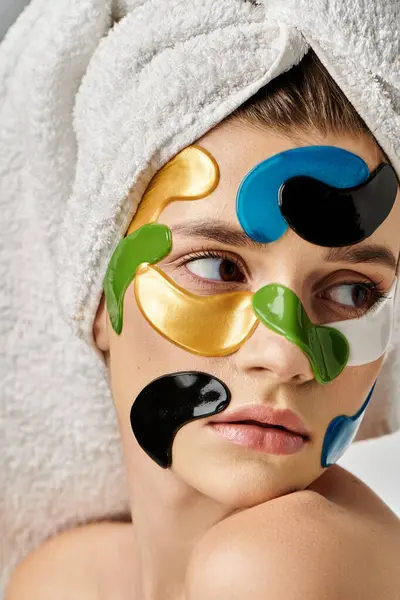 Une jeune femme sereine, portant des bandeaux oculaires et une serviette enroulée autour de sa tête, respire la relaxation et l'autosoin. — Photo de stock