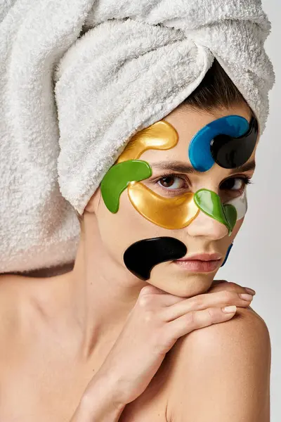 Una mujer con una toalla en la cabeza con manchas en los ojos en la cara. - foto de stock
