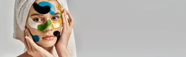 A young woman in a tranquil pose, sporting a towel turban on her head with eye patches on her face. — Stock Photo