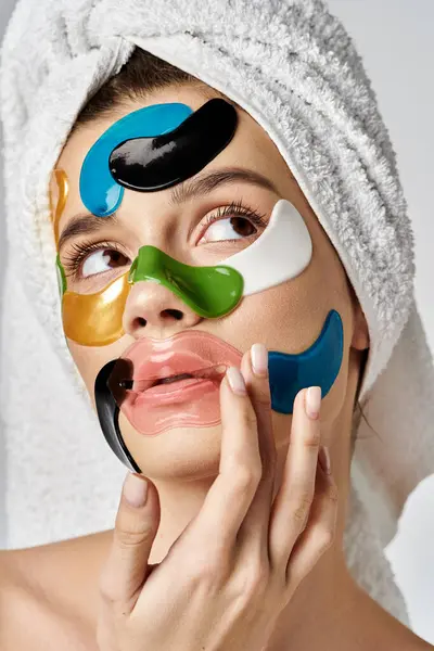 Una mujer serena con una toalla en la cabeza y parches en los ojos, exudando relajación y cuidado personal. - foto de stock