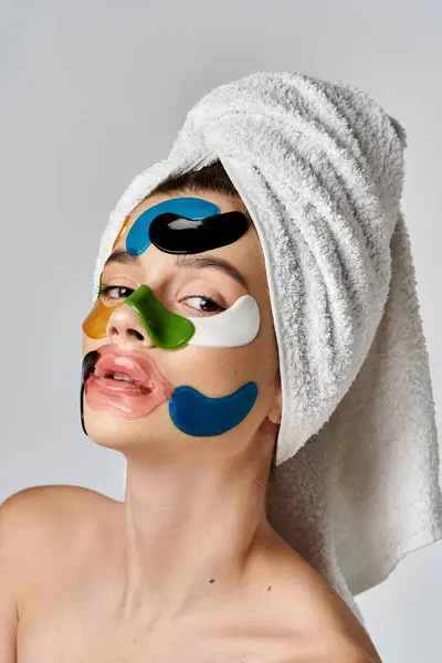 Une jeune femme avec un turban serviette sur la tête, mettant en valeur les patchs de visage artistique. — Photo de stock