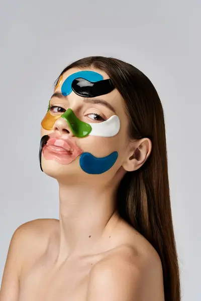 Una hermosa joven con parches en la cara, mostrando un cambio de imagen creativo y artístico. - foto de stock