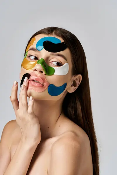 Une jeune femme avec des patchs sur le visage ornant son visage, exsudant une aura mystérieuse et captivante. — Photo de stock