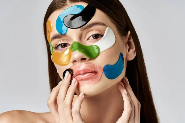 Una giovane donna con macchie sugli occhi sul viso creando una dichiarazione audace con colori accattivanti. — Foto stock