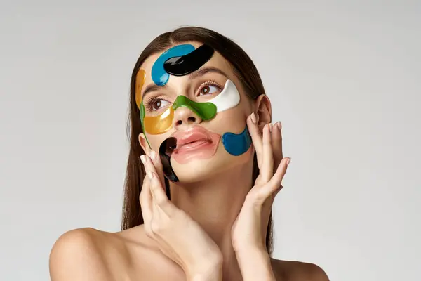Eine schöne junge Frau mit Augenklappen auf dem Gesicht in leuchtenden Farben, die Kreativität und Selbstausdruck zur Schau stellt. — Stockfoto