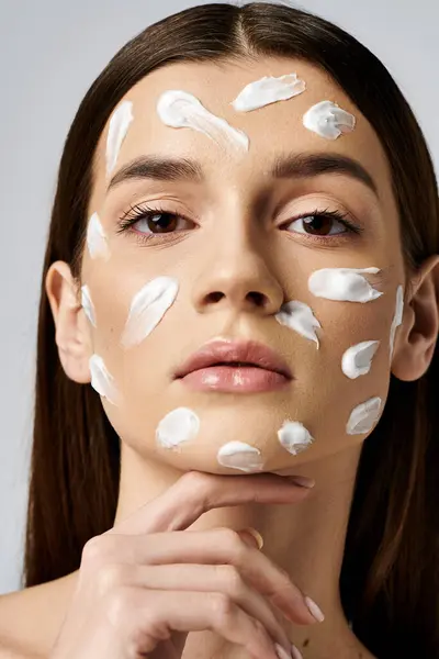 Una giovane donna con una generosa quantità di crema sul viso, migliorando la sua routine di cura della pelle. — Foto stock