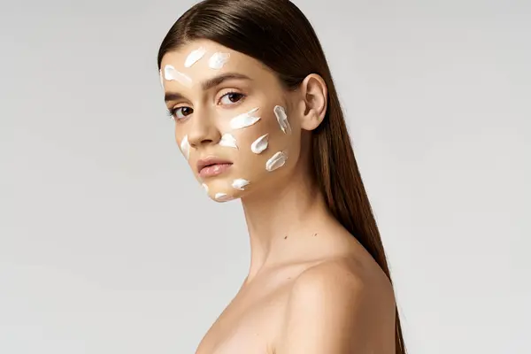 A young woman posing with a thick layer of cream on her face, creating a whimsical and surreal image. — Stock Photo
