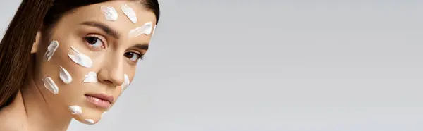 A stunning young woman with white cream on her face, exuding elegance and beauty. — Stock Photo