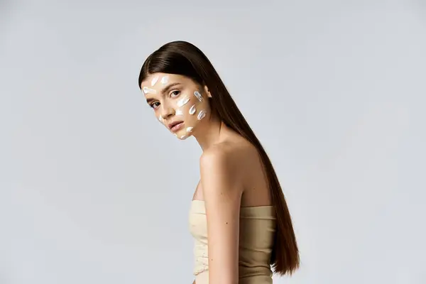 Una giovane donna in mostra un look mozzafiato con intricata crema bianca sul viso, sottolineando le sue caratteristiche elegantemente. — Foto stock