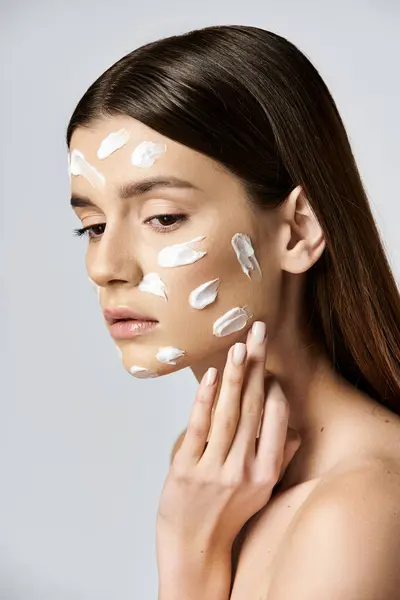 A beautiful young woman wearing a white cream on her face, exuding mystery and intrigue. — Stock Photo