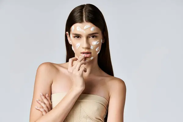 A beautiful young woman posing with white cream on her face, creating a stunning, ethereal look. — Stock Photo