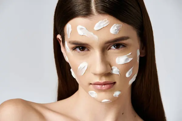 A woman adorned with a generous amount of cream on her face, exuding freshness and beauty. — Foto stock