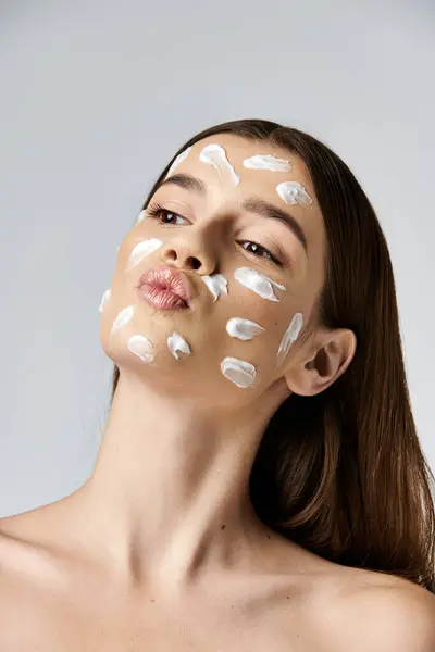 Uma jovem com um creme branco delicadamente adorna seu rosto, exalando um ar de mistério e elegância. — Fotografia de Stock