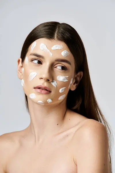 A stunning young woman wearing a white cream on her face, exuding mystery and elegance. — Stock Photo