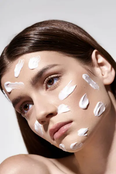 A beautiful young woman with striking white cream on her face, posing artistically. — Stock Photo