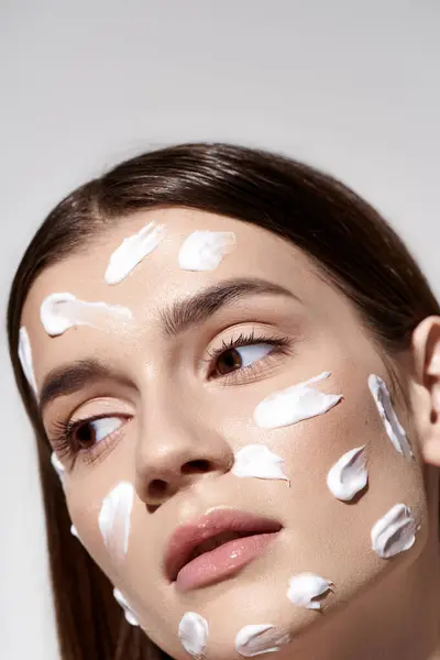 A stunning young woman posing with an abundance of white cream on her face, enhancing her natural beauty. — Stock Photo