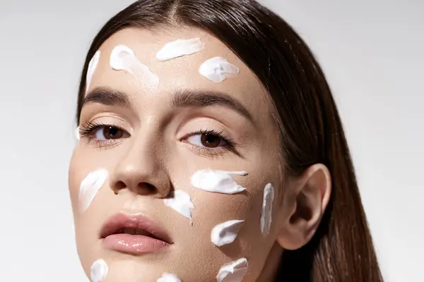 A beautiful young woman posing with an abundance of cream on her face. — Stock Photo